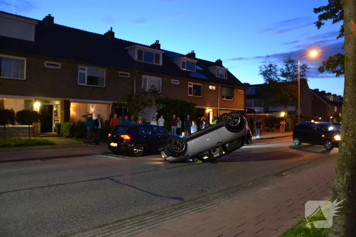 Auto op zijn kop na botsing met geparkeerde auto
