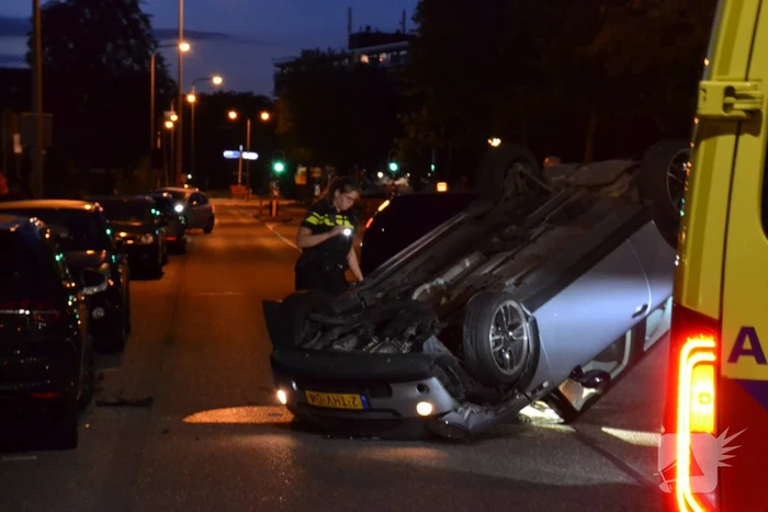 Auto op zijn kop na botsing met geparkeerde auto