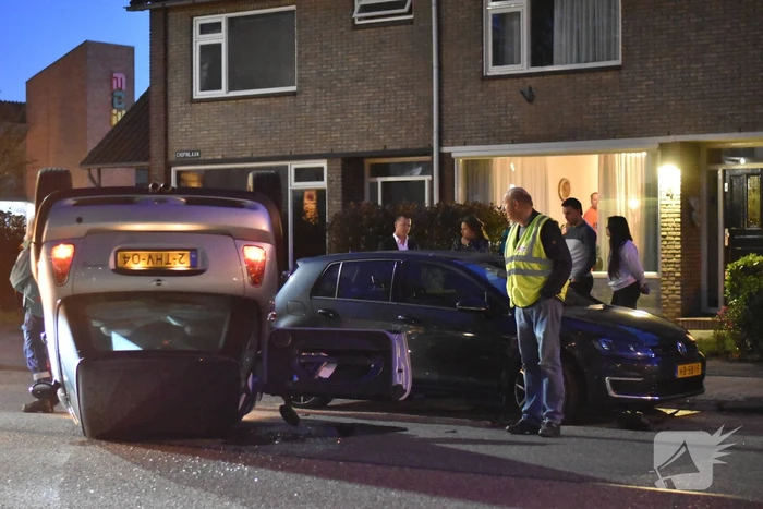 Auto op zijn kop na botsing met geparkeerde auto