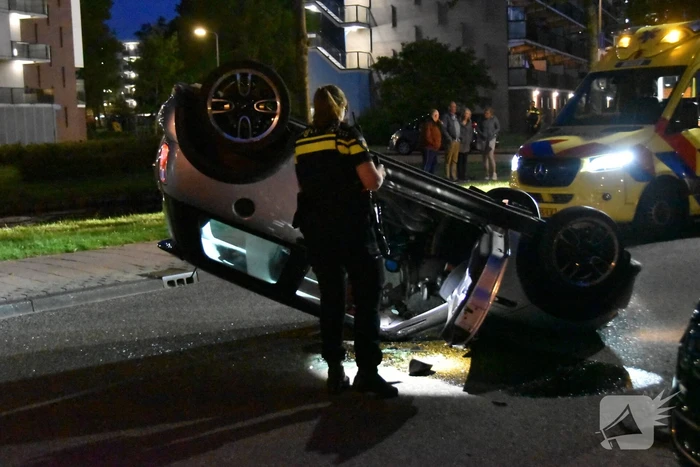 Auto op zijn kop na botsing met geparkeerde auto