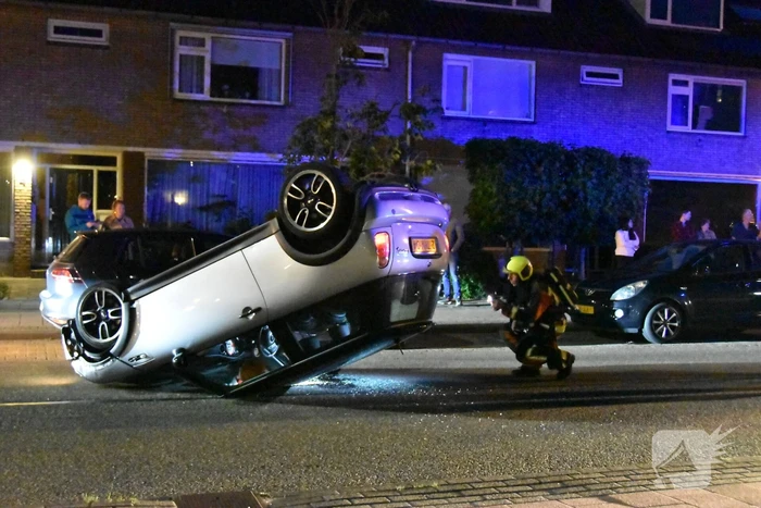 Auto op zijn kop na botsing met geparkeerde auto