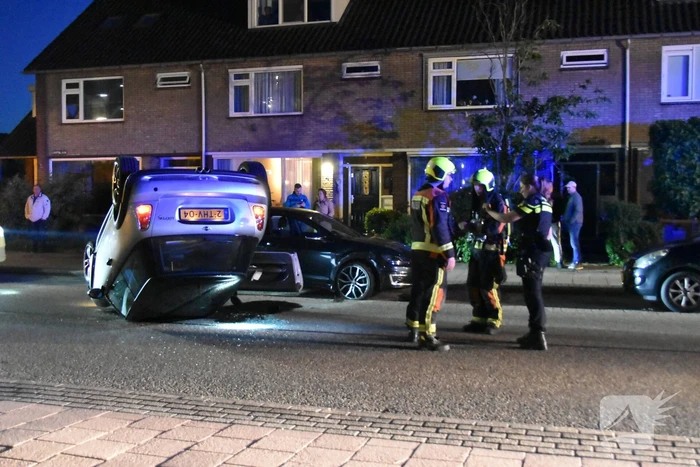 Auto op zijn kop na botsing met geparkeerde auto