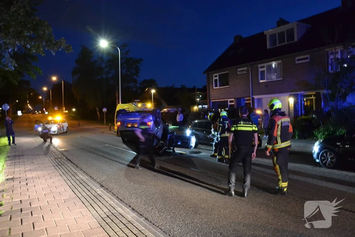 Auto op zijn kop na botsing met geparkeerde auto