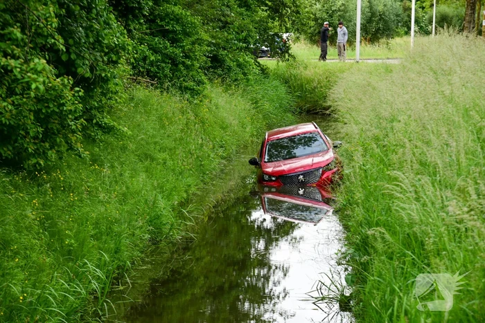 Auto rijdt over rotonde de sloot in