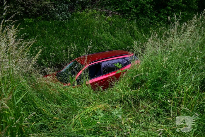 Auto rijdt over rotonde de sloot in