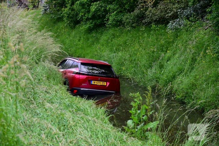 Auto rijdt over rotonde de sloot in