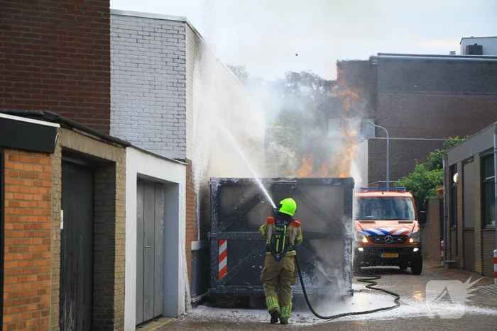 Vlammen slaan uit bouwcontainer met afval
