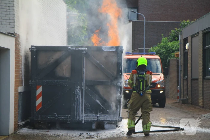 Vlammen slaan uit bouwcontainer met afval