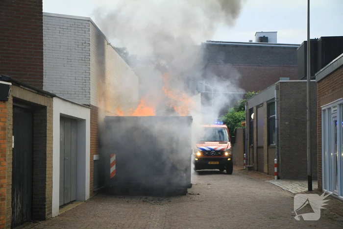 Vlammen slaan uit bouwcontainer met afval