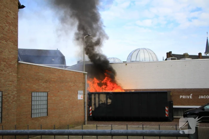 Vlammen slaan uit bouwcontainer met afval