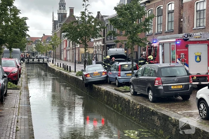 Auto bengelt op rand van gracht