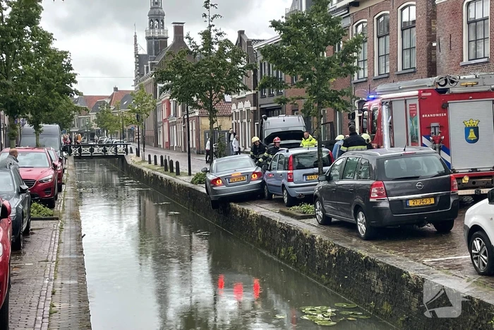 Auto bengelt op rand van gracht