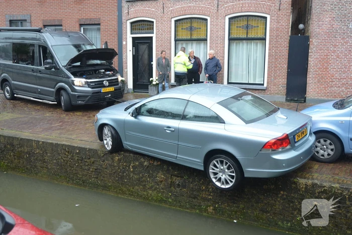 Auto bengelt op rand van gracht