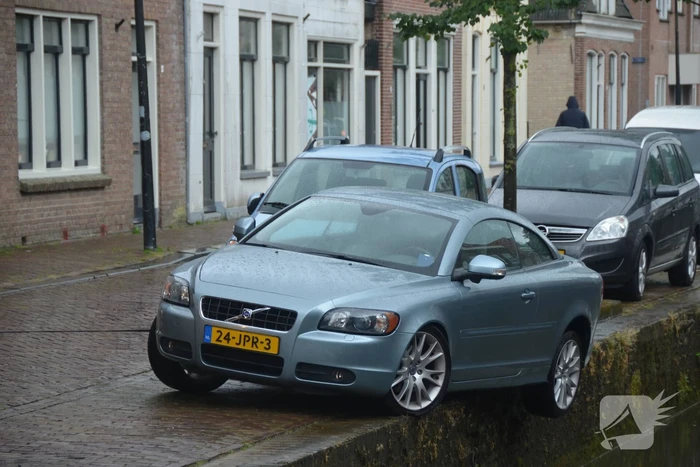 Auto bengelt op rand van gracht