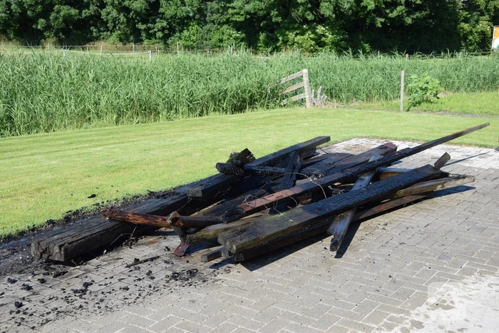 Houten balken achter schuur vlam gevat