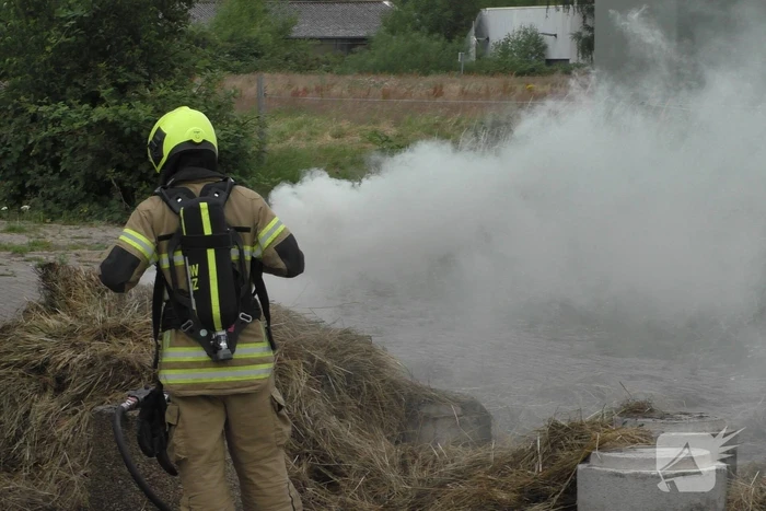 Brandweer blust brandende hooibaal