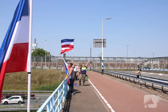 Actievoerders zwaaien met omgekeerde vlaggen naar verkeer op A15