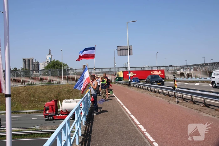 Actievoerders zwaaien met omgekeerde vlaggen naar verkeer op A15