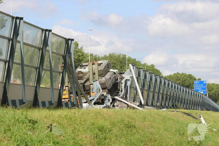 Vrachtwagen met gevechtstank boort zich in geluidswal