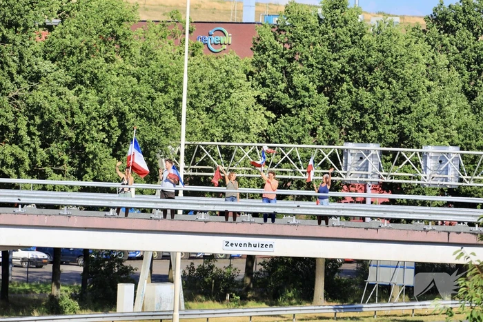 Verontrustende burgers staan met omgekeerde vlaggen zwaaien naar verkeer op A1