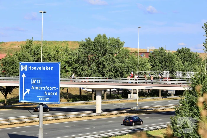 Verontrustende burgers staan met omgekeerde vlaggen zwaaien naar verkeer op A1