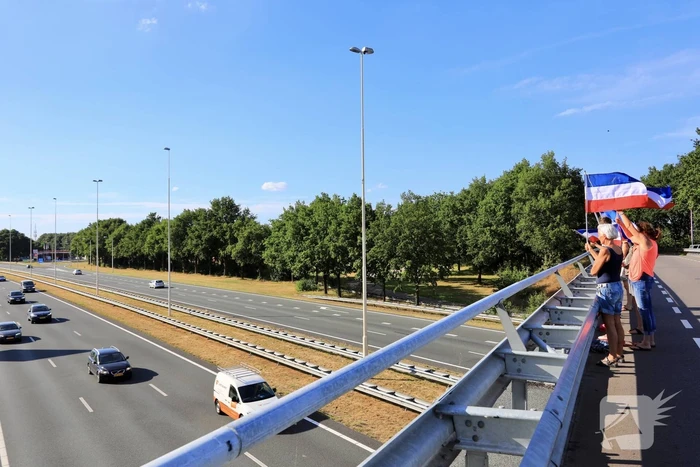 Verontrustende burgers staan met omgekeerde vlaggen zwaaien naar verkeer op A1