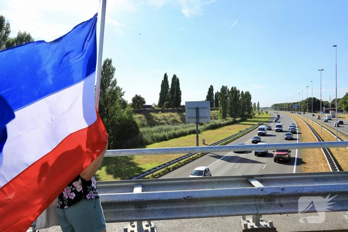 Verontrustende burgers staan met omgekeerde vlaggen zwaaien naar verkeer op A1