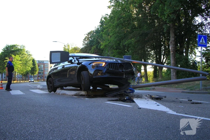 Personenauto uit de bocht, lantaarnpaal geraakt