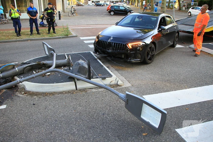 Personenauto uit de bocht, lantaarnpaal geraakt