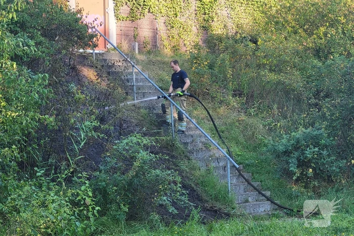 Brandweer blust bermbrand naast treinspoor