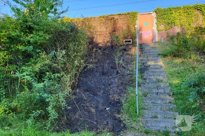 Brandweer blust bermbrand naast treinspoor