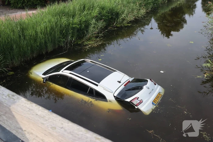 Auto raakt te water naast brug