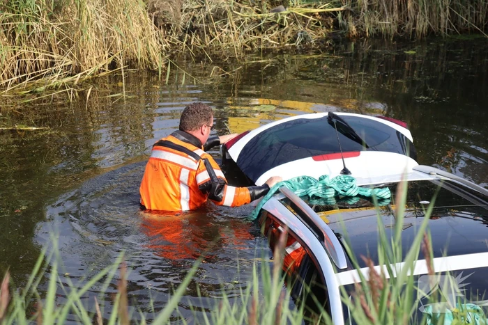 Auto raakt te water naast brug