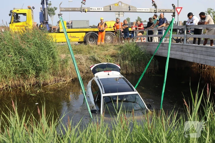 Auto raakt te water naast brug