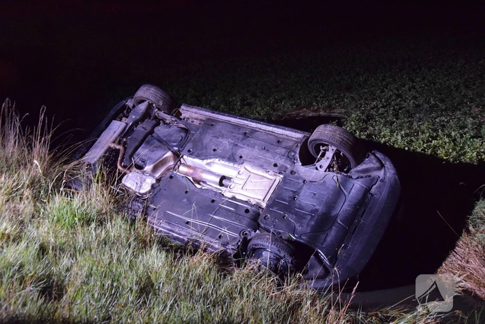 Auto op zijn kop in sloot naast talud
