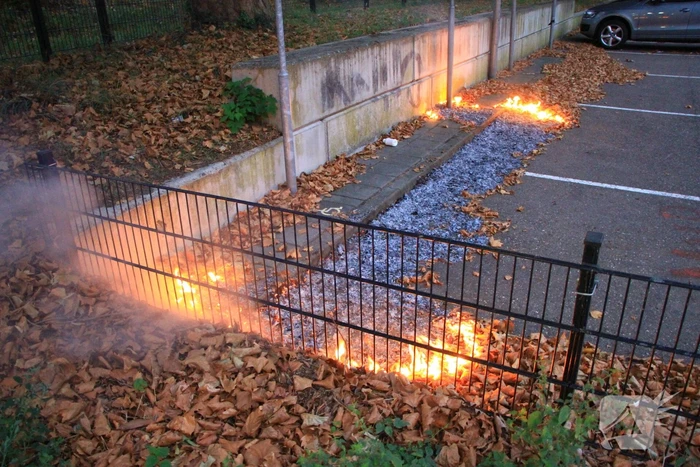 Bladeren vliegen in brand op parkeerterrein