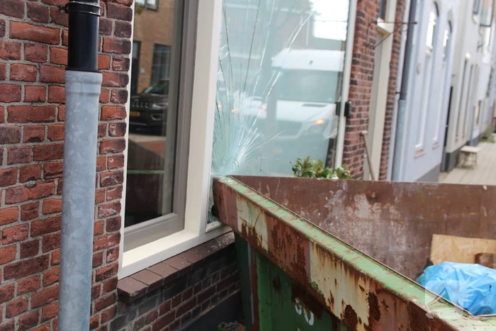 Pakketbezorger botst tegen bouwcontainer en knalt tegen woning