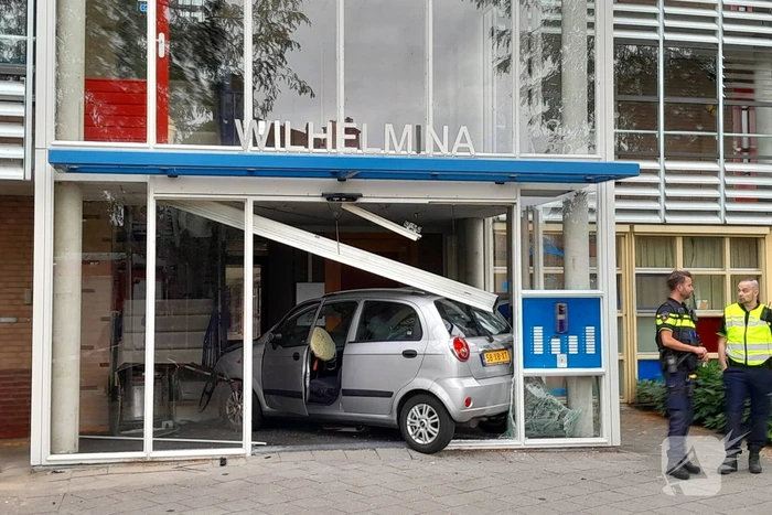 Bestuurster ramt met auto entree flatgebouw