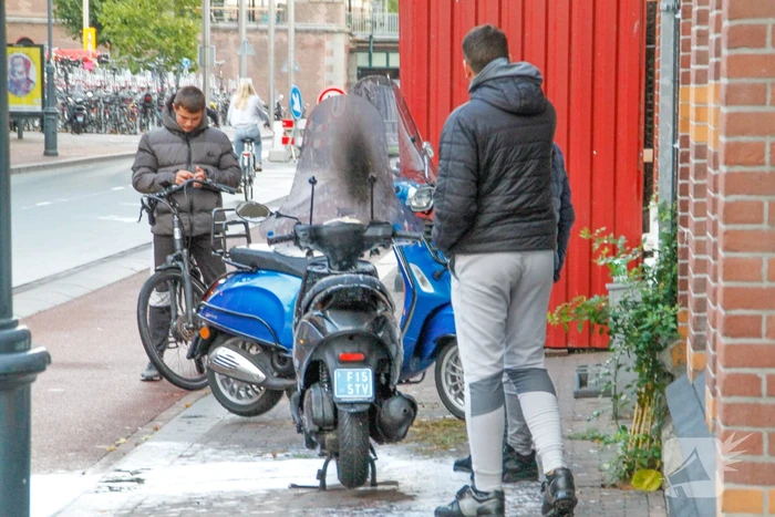 Omstanders blussen brandende scooter
