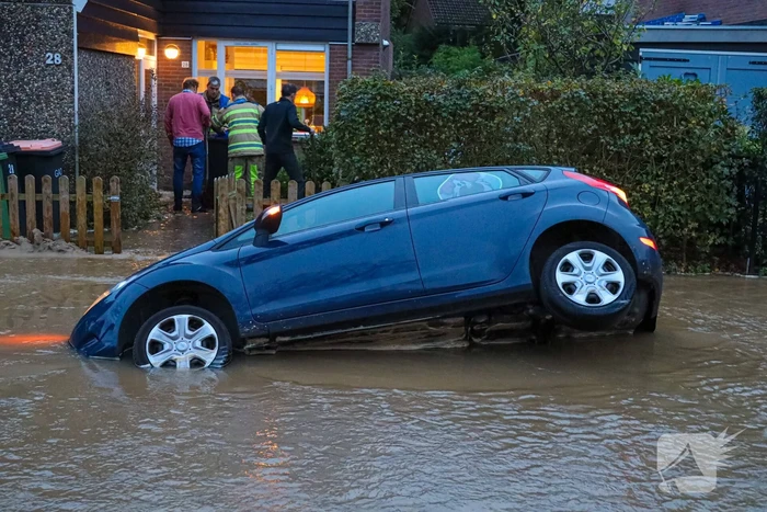 Auto zakt in sinkhole door gesprongen hoofdwaterleiding