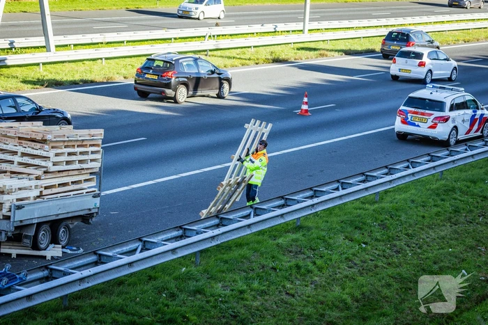 Automobilist verliest overbeladen aanhangwagen met pallets en crasht