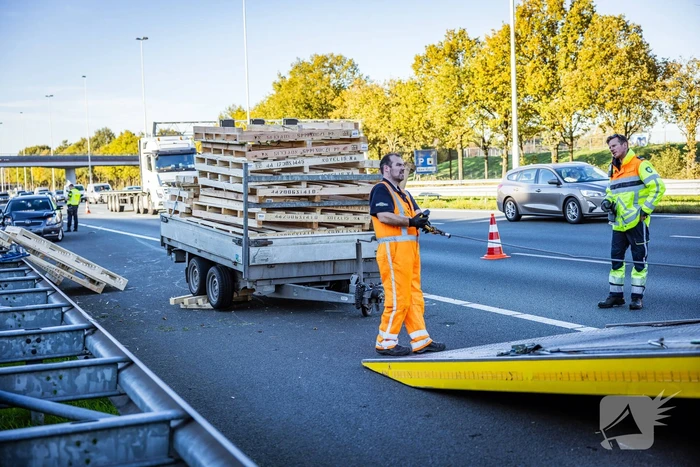Automobilist verliest overbeladen aanhangwagen met pallets en crasht