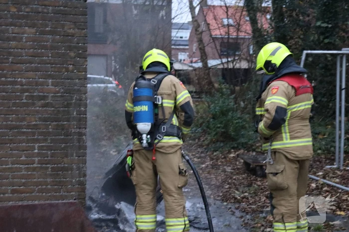 Wasmachine in brand tegen gebouw
