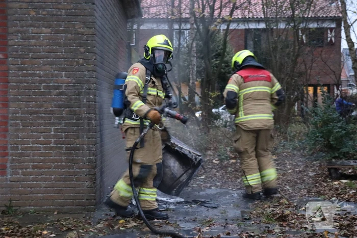 Wasmachine in brand tegen gebouw