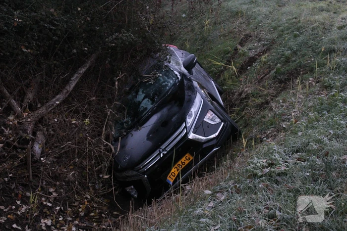 Auto raakt van de weg en belandt half in de sloot