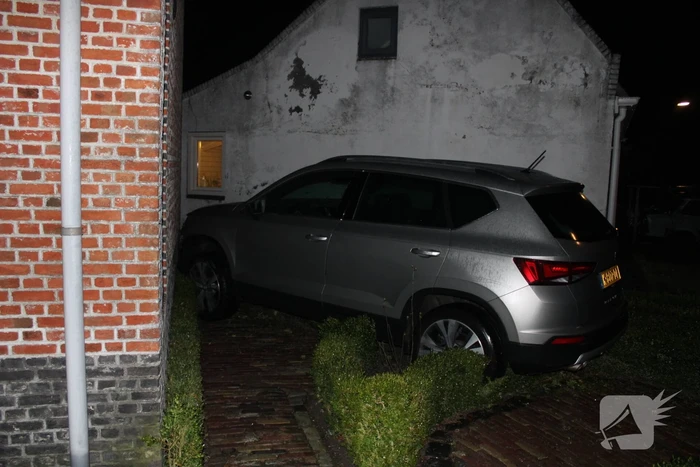 Auto glijdt door tegen woning