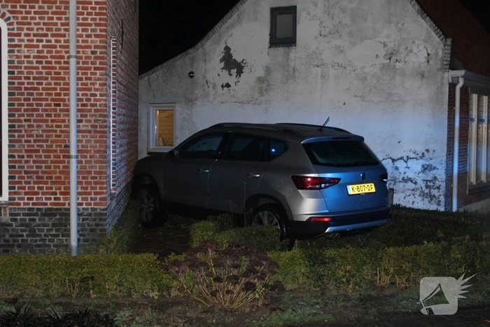 Auto glijdt door tegen woning