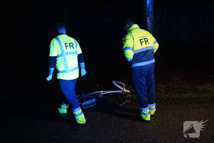 Hulp aan gevallen fietster op donkere weg