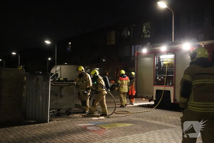 Brandweer blust brandende papiercontainer