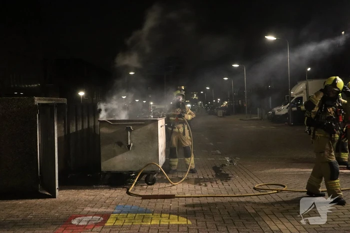 Brandweer blust brandende papiercontainer